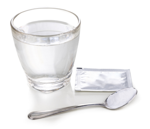 Water glass with spoon and sachet of white powder medicine
